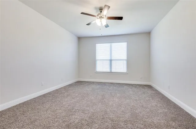 an empty room with windows and ceiling fan