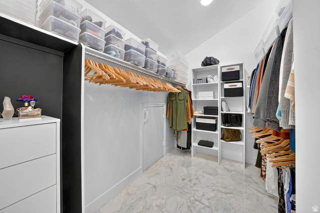 1979 Cave Hollow Way Bountiful, UT 84010 - Photo 30 of 59 2nd Floor Spacious walk-in closet featuring light-toned tile flooring, extensive hanging rods, multiple built-in shelving units, and a dedicated dresser space