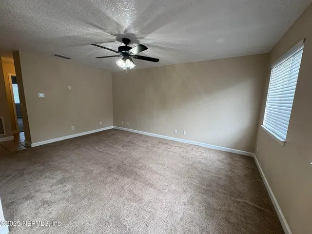 an empty room with windows and fan