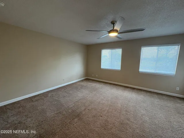 an empty room with windows and fan