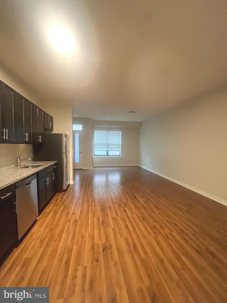 a view of a kitchen with wooden floor and stainless steel appliances