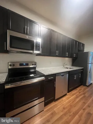 a kitchen with wooden floors and black appliances