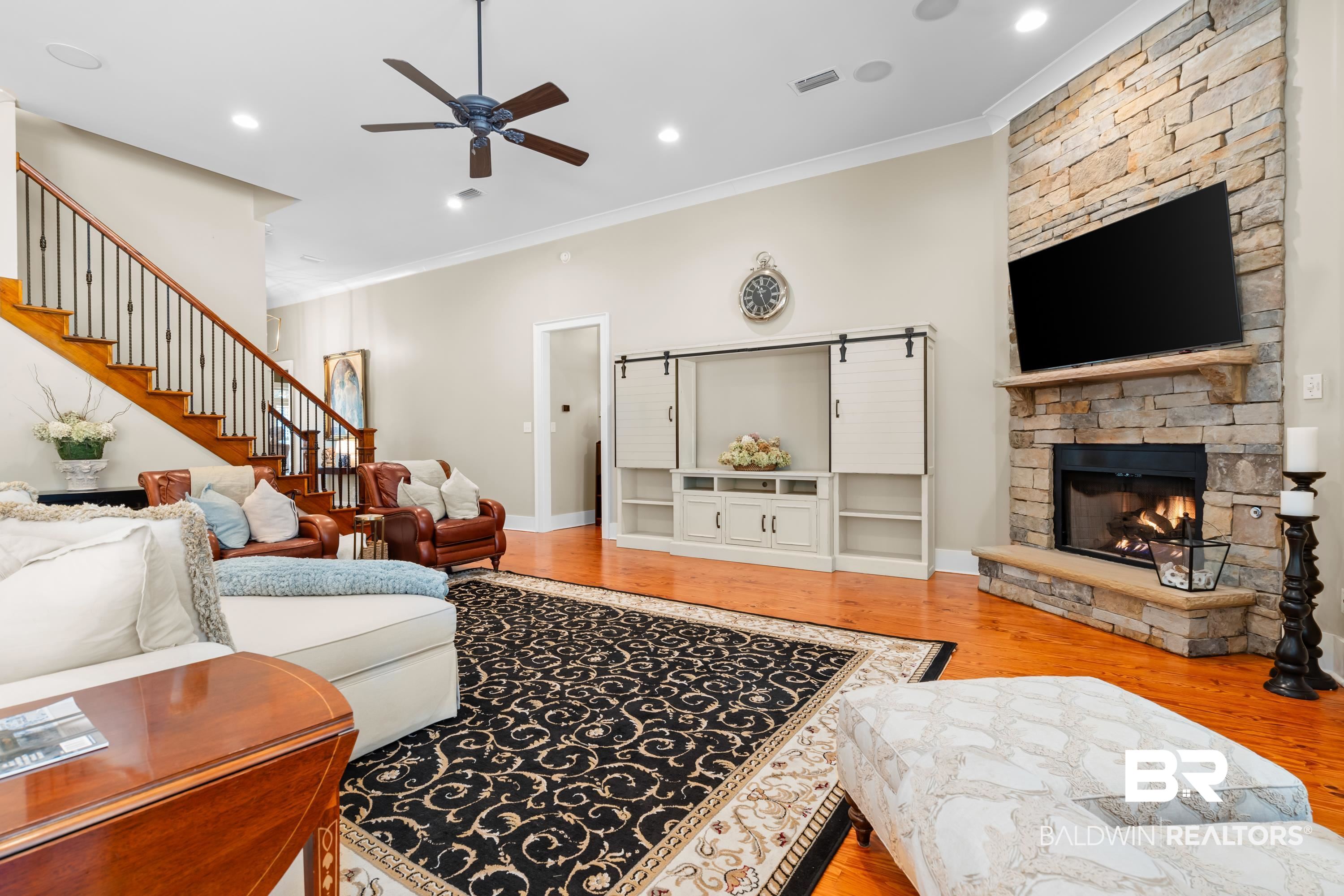 30057 Dolive Ridge Daphne, AL 36527 - Photo 11 of 55 Living room with a stone fireplace, light wood-type flooring, ceiling fan, and crown molding