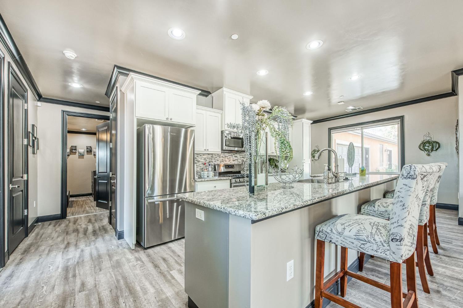 12629 Bronco Road Madera, CA 93636 - Photo 93 of 94 a kitchen with stainless steel appliances granite countertop a refrigerator a sink dishwasher a dining table and chairs with wooden floor