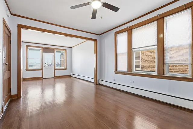 a view of an empty room with window and wooden floor