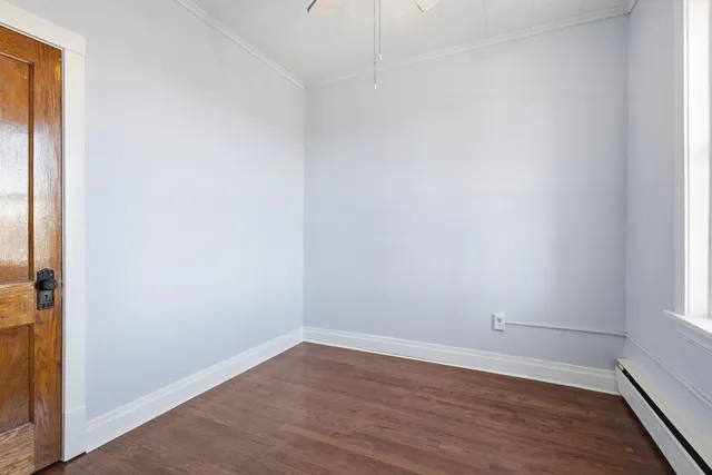 a view of an empty room and wooden floor and a window