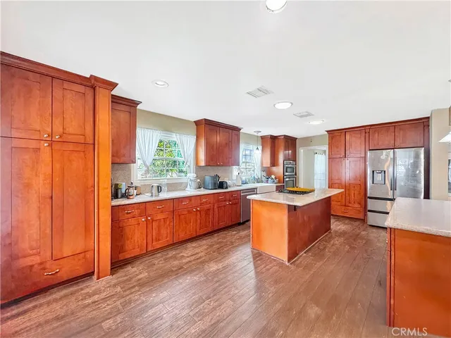 a large kitchen with stainless steel appliances granite countertop a refrigerator a sink dishwasher a stove and wooden floors