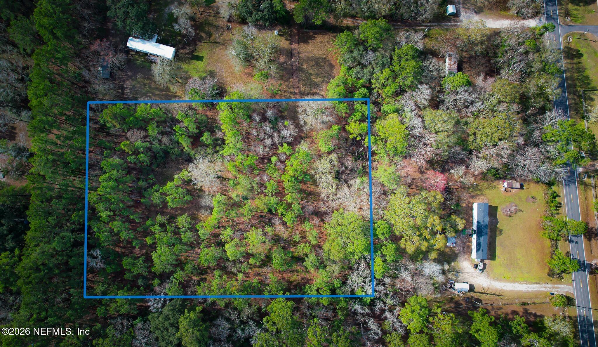 an aerial view of residential house with outdoor space and trees all around