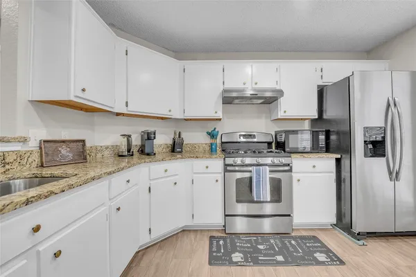 a kitchen with stainless steel appliances granite countertop a sink stove and refrigerator