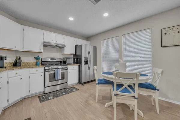 a kitchen with a white cabinets and chairs in it
