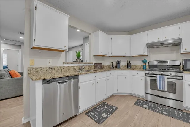 a kitchen with granite countertop cabinets stainless steel appliances and a counter space