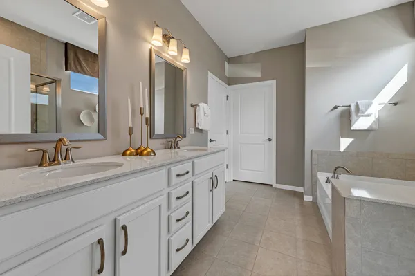 a spacious bathroom with a double vanity sink a mirror and a shower