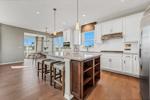 a kitchen with stainless steel appliances granite countertop a stove a sink dishwasher and a refrigerator with wooden floor