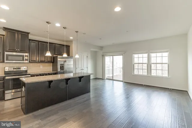 a large kitchen with stainless steel appliances granite countertop a stove a sink dishwasher and a microwave oven with wooden floor