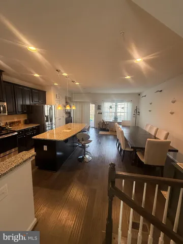 a living room with stainless steel appliances furniture a rug and a kitchen view