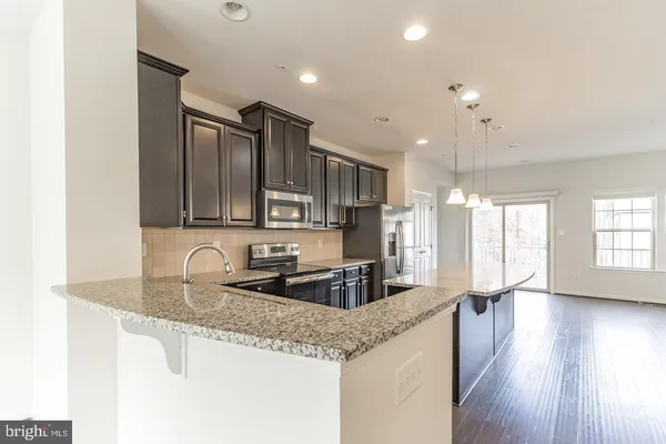 a kitchen with granite countertop a sink and refrigerator