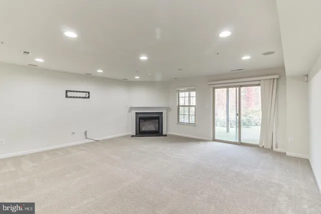 an empty room with windows and fireplace