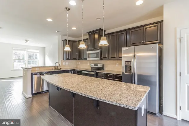 a large kitchen with granite countertop a sink counter space stainless steel appliances and cabinets