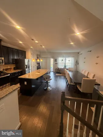 a living room with stainless steel appliances furniture a rug and a kitchen view