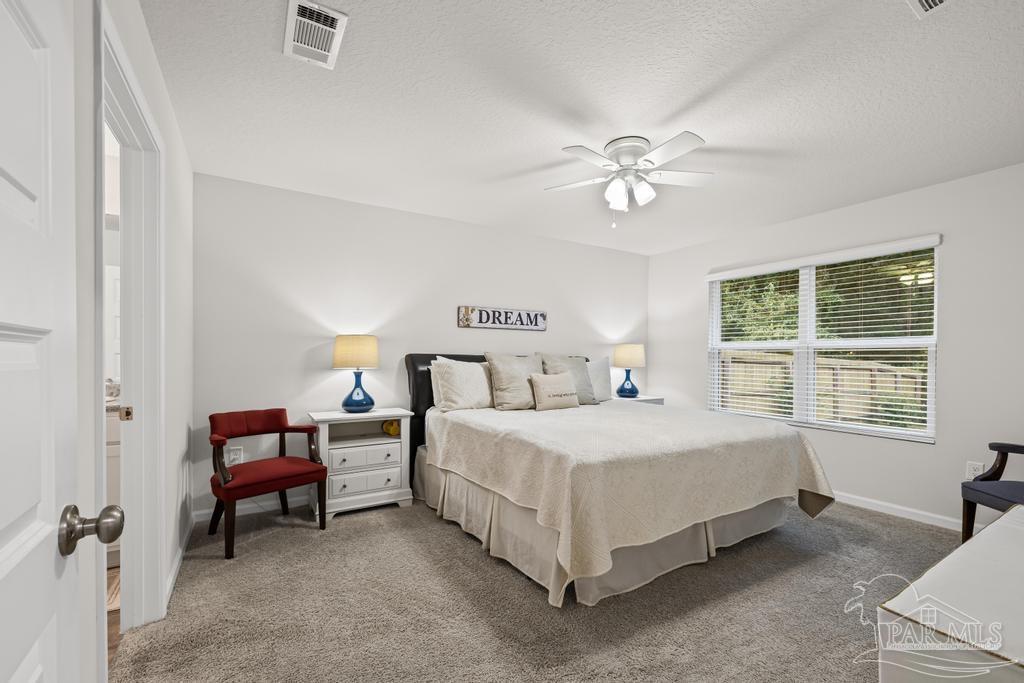 5443 Peach Drive Pace, FL 32571 - Photo 21 of 34 a spacious bedroom with a bed and a chandelier
