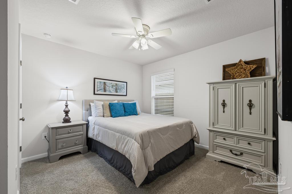 5443 Peach Drive Pace, FL 32571 - Photo 26 of 34 a bedroom with a large bed and a chandelier