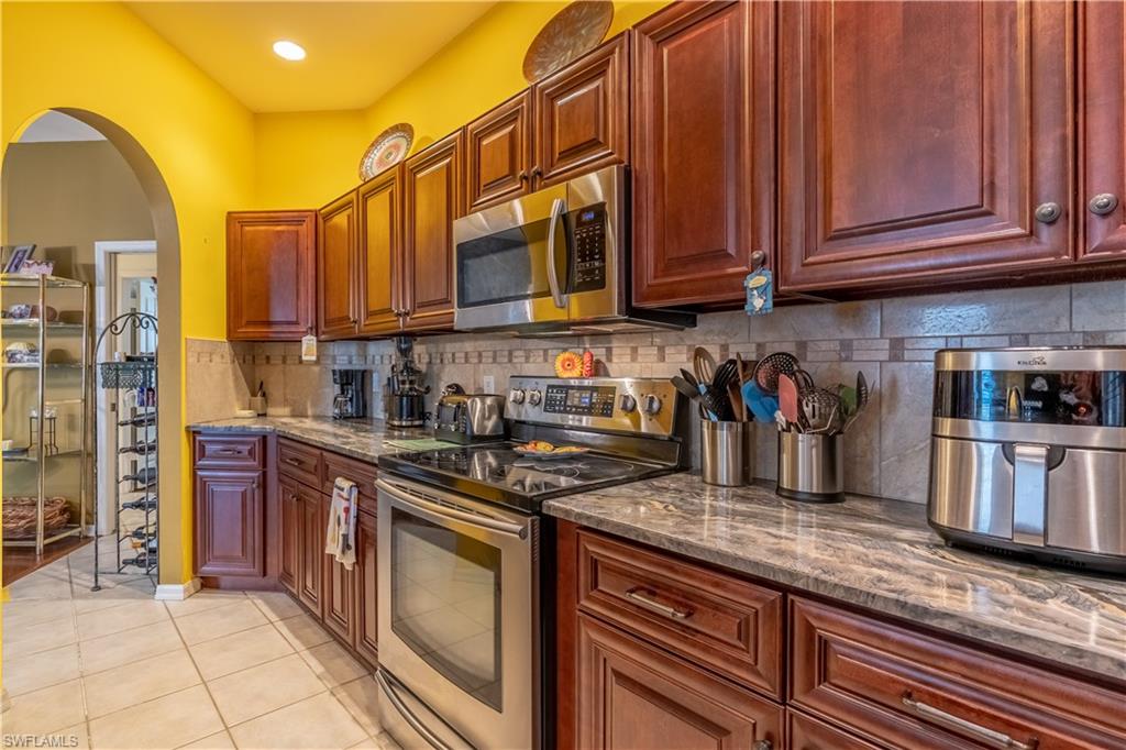 431 Crossfield Circle, Unit 77 Naples, FL 34104 - Photo 14 of 33 a kitchen with stainless steel appliances granite countertop a stove a sink dishwasher and cabinets with wooden floor
