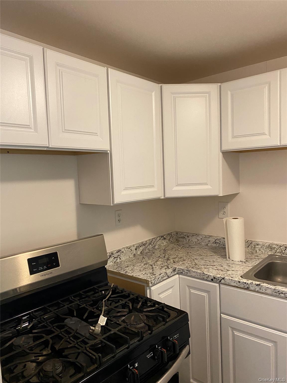 84-24 98th Street, Unit 1 Queens, NY 11421 - Photo 5 of 22 a kitchen with granite countertop white cabinets and white appliances