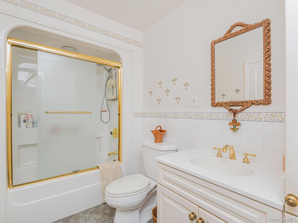 105 Douglas Road Chappaqua, NY 10514 - Photo 20 of 33 Full Bathroom featuring vanity, tile walls, shower / bath combination with glass door, and wainscoting