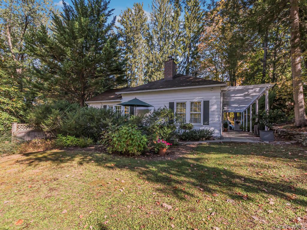 105 Douglas Road Chappaqua, NY 10514 - Photo 31 of 33 Rear view of property with a yard, a chimney, a carport, and view of scattered trees