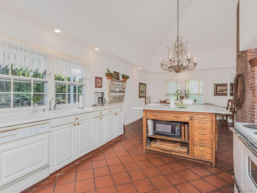 105 Douglas Road Chappaqua, NY 10514 - Photo 10 of 33 Kitchen featuring white appliances, light countertops, white cabinets, lofted ceiling, and decorative light fixtures