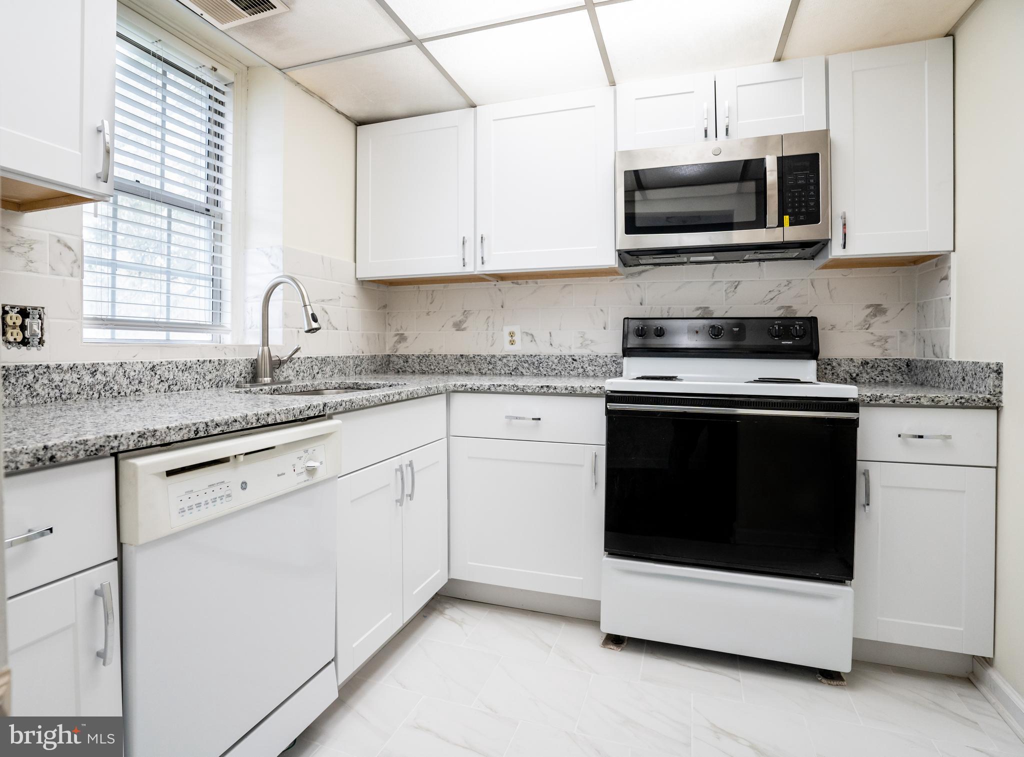 4814 30th Street South, Unit B1 Arlington, VA 22206 - Photo 10 of 18 a kitchen with stainless steel appliances granite countertop white cabinets a microwave a sink and a counter