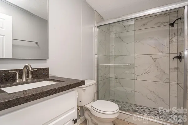 a bathroom with a granite countertop sink toilet and shower