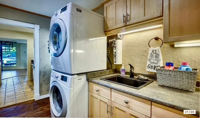a bathroom with a sink and a washing machine with wooden floor