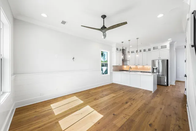 a view of a hallway with wooden floor and a bathroom