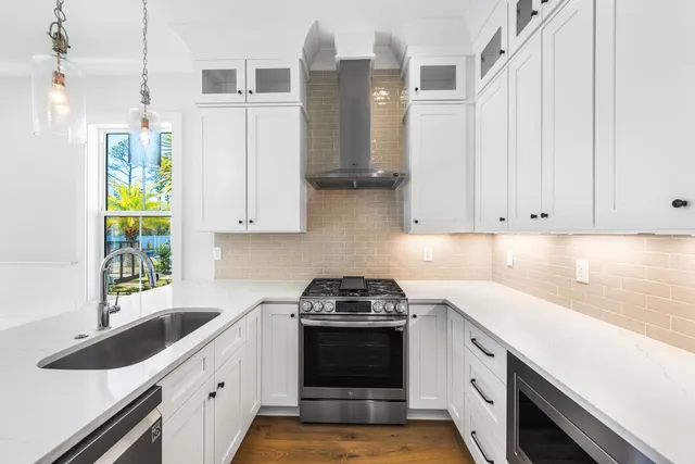 a kitchen with a sink and a stove with white cabinets