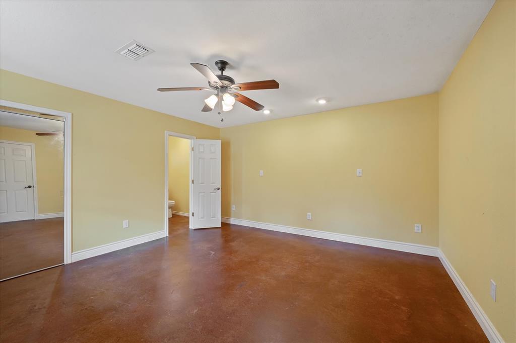1070 Piney Grove Road Rusk, TX 75785 - Photo 16 of 39 Unfurnished bedroom featuring finished concrete flooring, a ceiling fan, and ensuite bath
