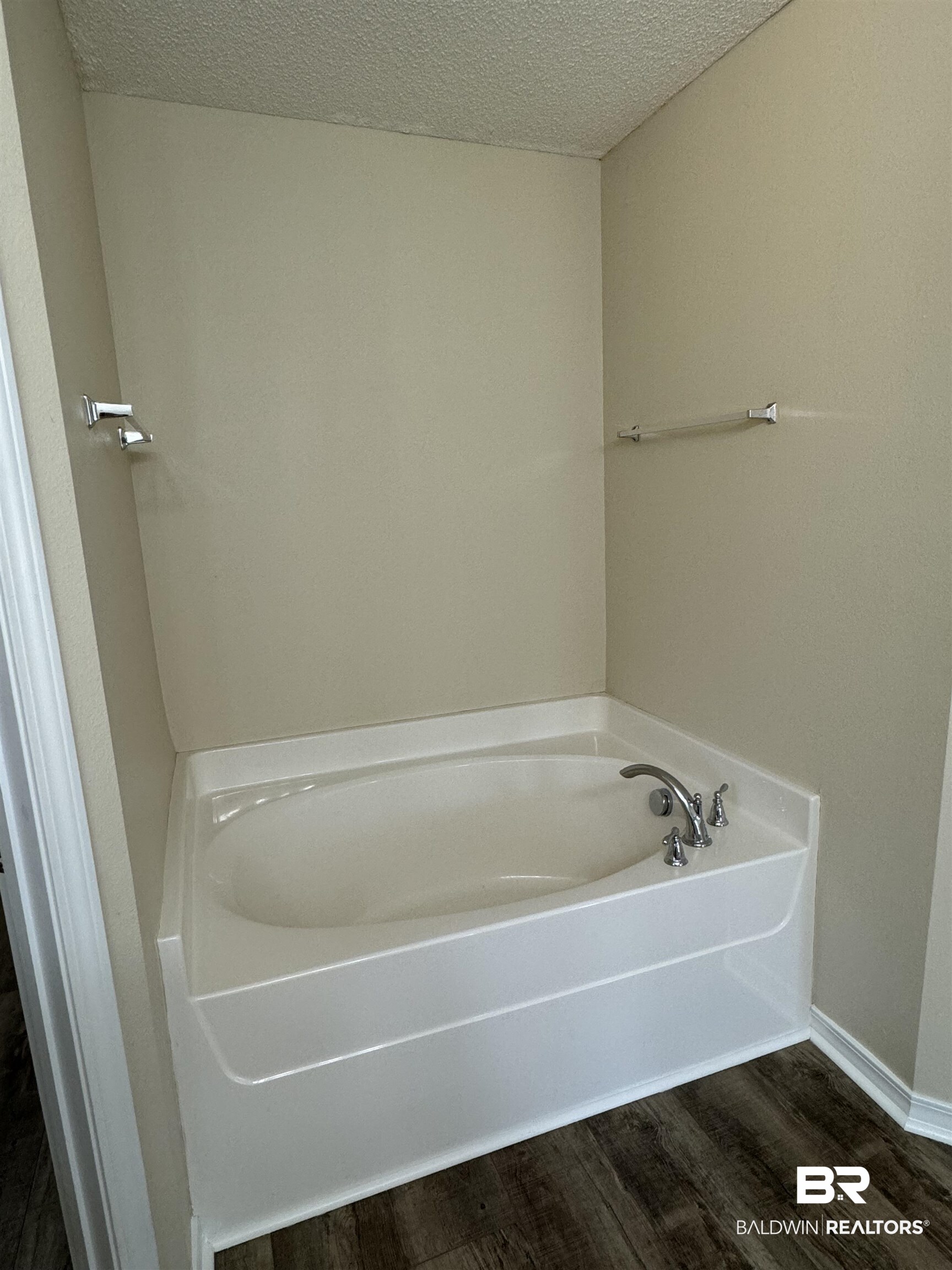 32769 Arbor Ridge Circle Lillian, AL 36549 - Photo 18 of 36 Bathroom with a textured ceiling, a tub to relax in, and hardwood / wood-style flooring
