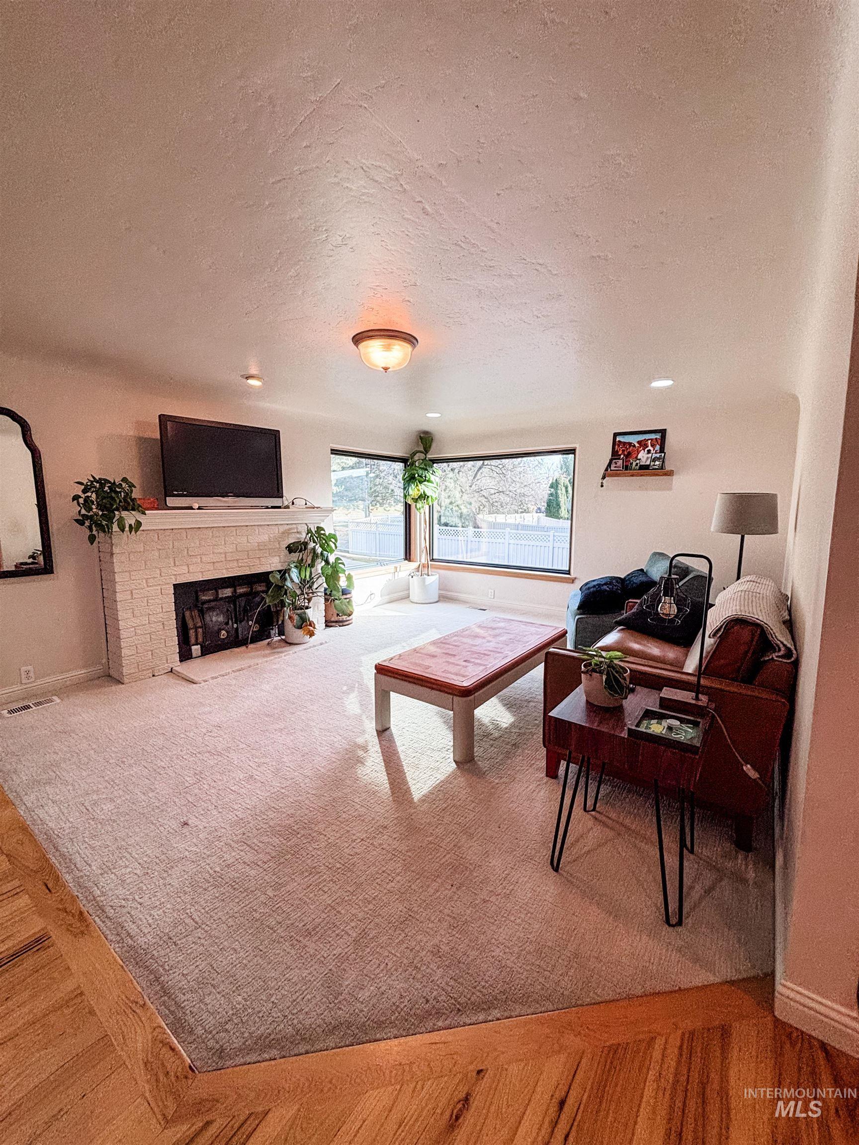743 North Horseshoe Bend Road Eagle, ID 83616 - Photo 4 of 27 Living area featuring a textured ceiling, a brick fireplace, and light wood finished floors