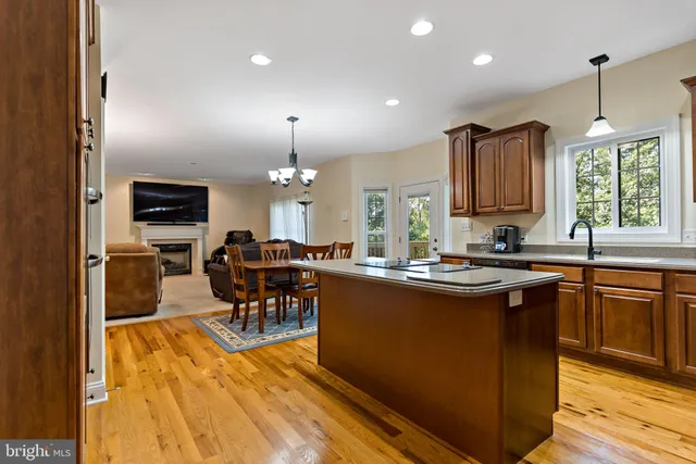 a kitchen with stainless steel appliances granite countertop a stove top oven a sink dishwasher a dining table and chairs with wooden floor