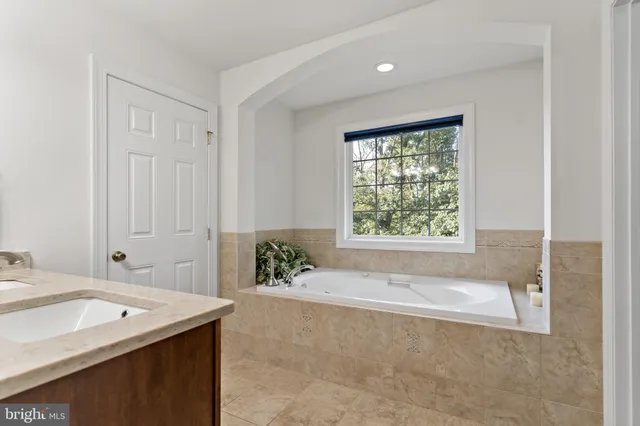 a spacious bathroom with a tub sink and mirror