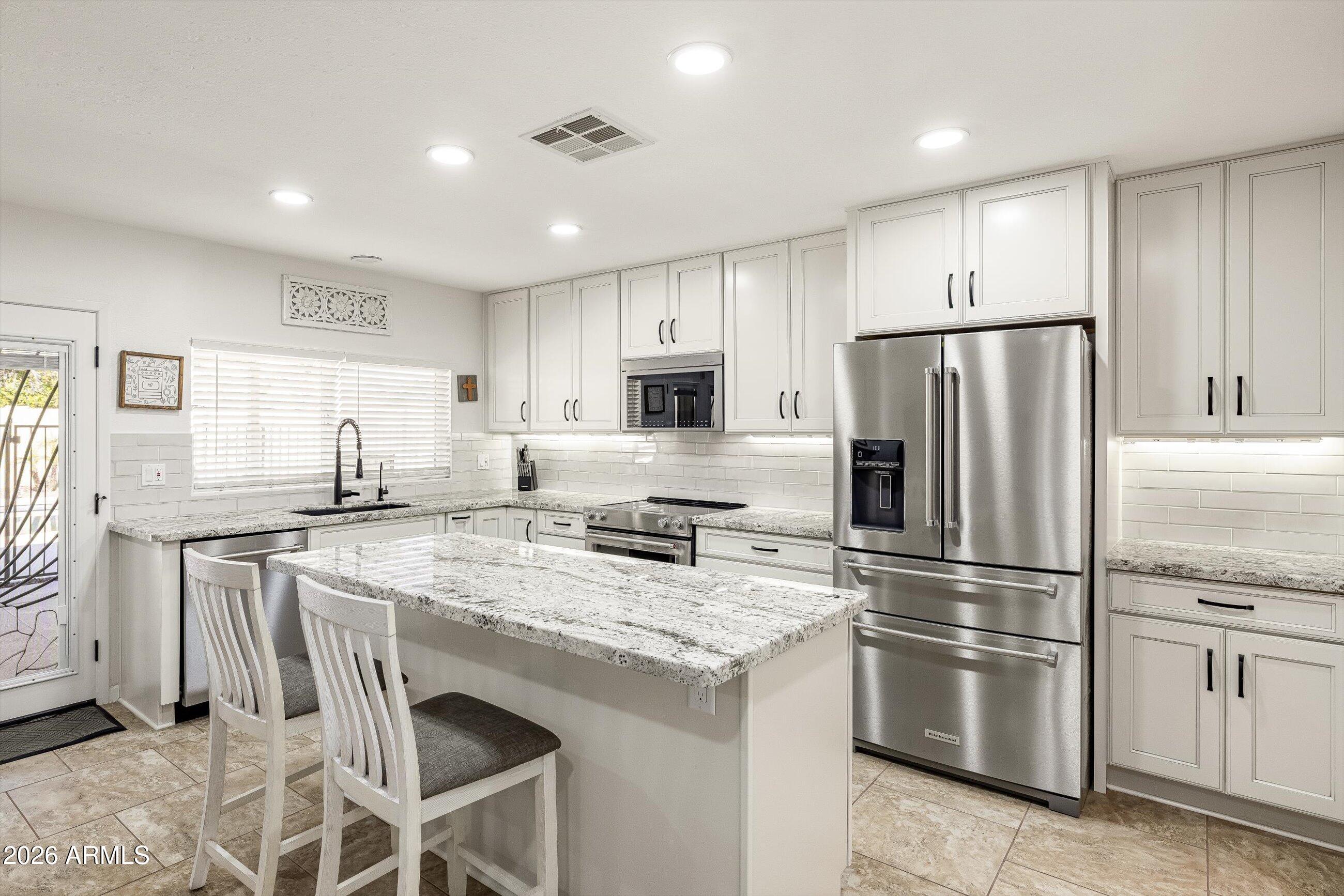 3024 West Wagoner Road Phoenix, AZ 85053 - Photo 9 of 34 a kitchen with stainless steel appliances granite countertop a refrigerator a stove a sink and a microwave
