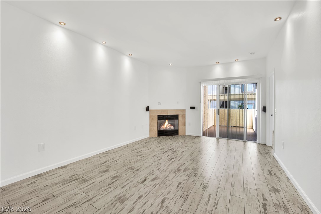 8725 West Flamingo Road, Unit 110 Las Vegas, NV 89147 - Photo 21 of 30 A cozy fireplace warms this room, featuring light-toned flooring and an inviting patio.