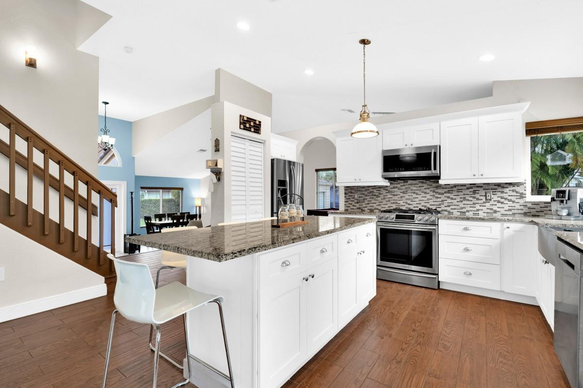 14809 Southwest 154th Court Miami, FL 33196 - Photo 11 of 30 a kitchen with stainless steel appliances kitchen island granite countertop a stove a sink and white cabinets with wooden floor