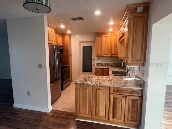 a kitchen with kitchen island granite countertop a refrigerator stove and oven with wooden floor