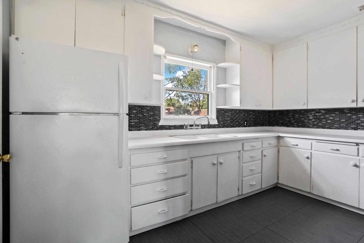 916 Elm Avenue Modesto, CA 95351 - Photo 13 of 52 14. Kitchen sink and cabinets Bright white cabinetry, generous counter space, and a window over the sink keep the kitchen feeling light, simple, and functional.
