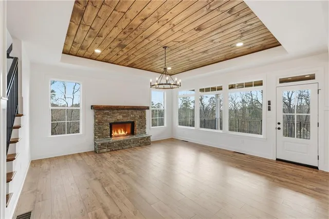 a view of an empty room with wooden floor fireplace and a window