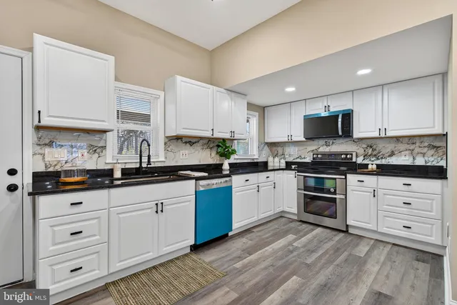 a kitchen with granite countertop white cabinets and stainless steel appliances