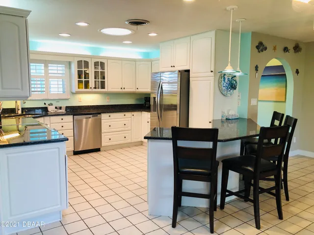 a kitchen with stainless steel appliances granite countertop a table chairs and a refrigerator
