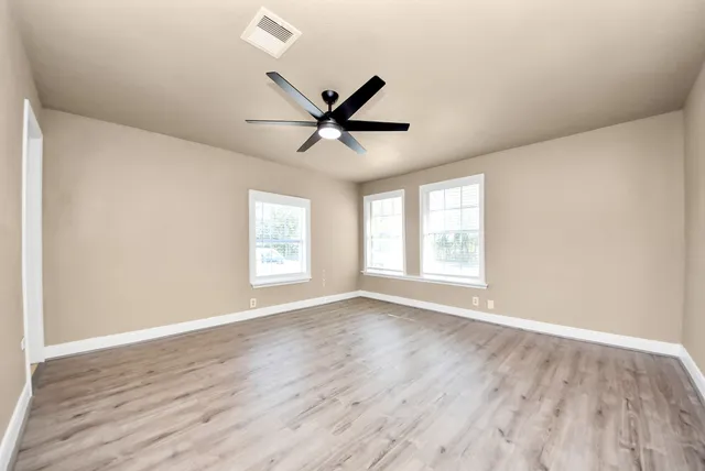 an empty room with wooden floor and windows
