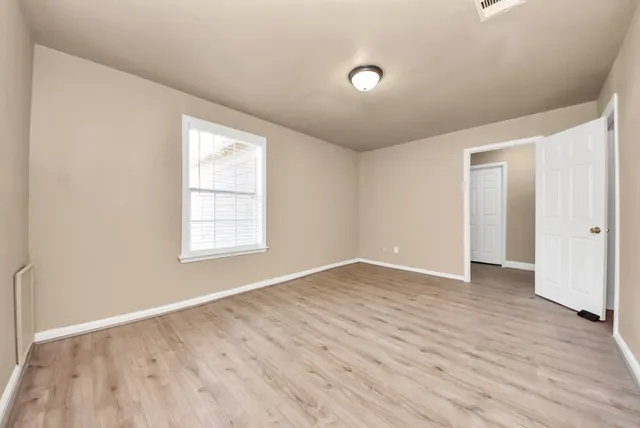 an empty room with wooden floor and windows
